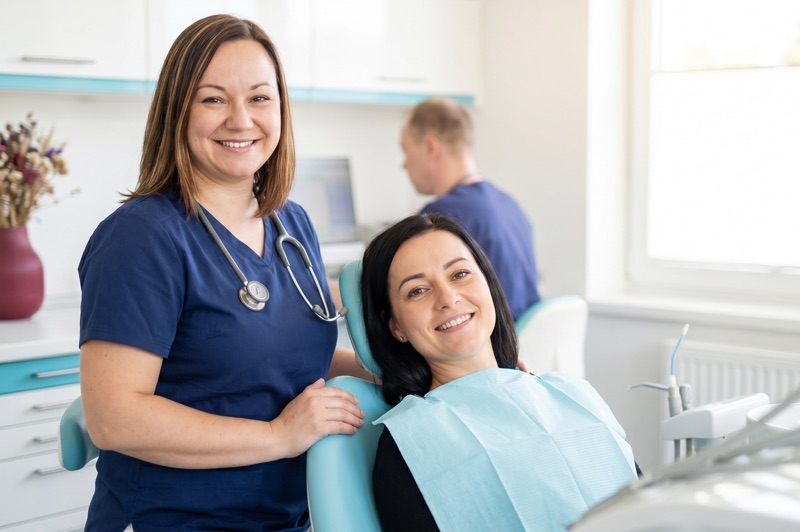Uśmiechnięta lekarka przy fotelu dentystycznym